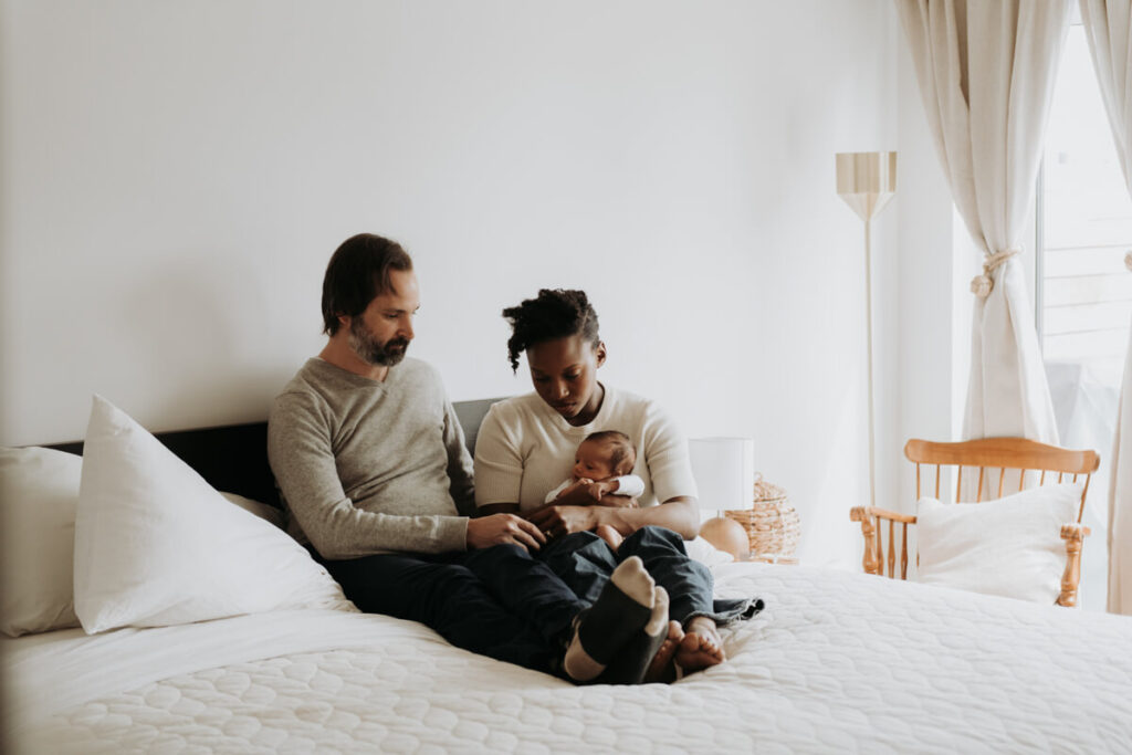 Mother and father sit up in their bed and mother has their newborn baby in her arms.

Newborn Photography. Brooklyn Newborn Portraits. Lifestyle Newborn Photographer. Brooklyn Family Photography.