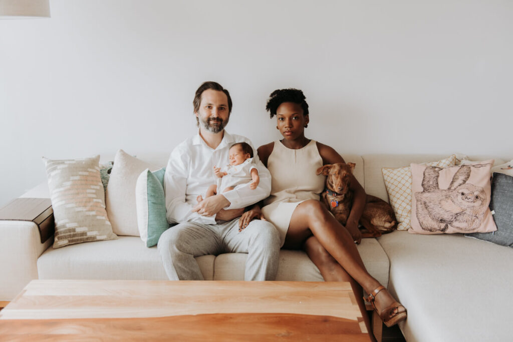 Mother and father sit on their couch with their newborn baby in the father's arms and their dog sitting next to the mother.

Newborn Photography. Brooklyn Newborn Portraits. Lifestyle Newborn Photographer. Brooklyn Family Photography.