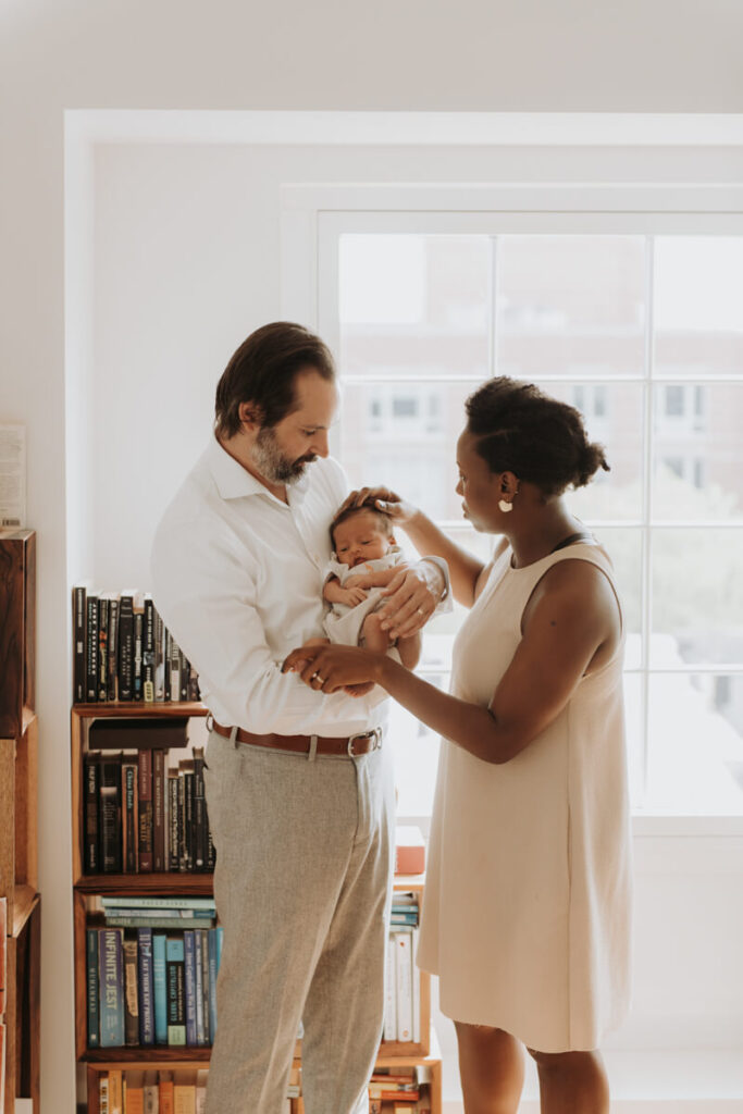 Father stands holding his newborn baby in his arms as the mother stands next to them and has her hand on her newborn baby's head.

Newborn Photography. Brooklyn Newborn Portraits. Lifestyle Newborn Photographer. Brooklyn Family Photography.