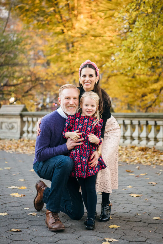 Husband and wife crouch down and hold their daughter as they all smile at the camera. Photographed in Central Park.

Manhattan Family Portraits. Central Park Family Photography. NYC Family Photographer.