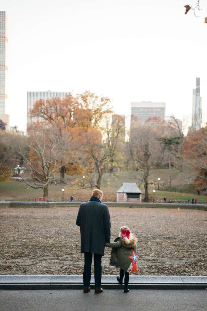 Father holding his daughter's hand. They are both facing away from the camera with the cit ahead of them. Photographed in Central Park.

Manhattan Family Portraits. Central Park Family Photography. NYC Family Photographer.