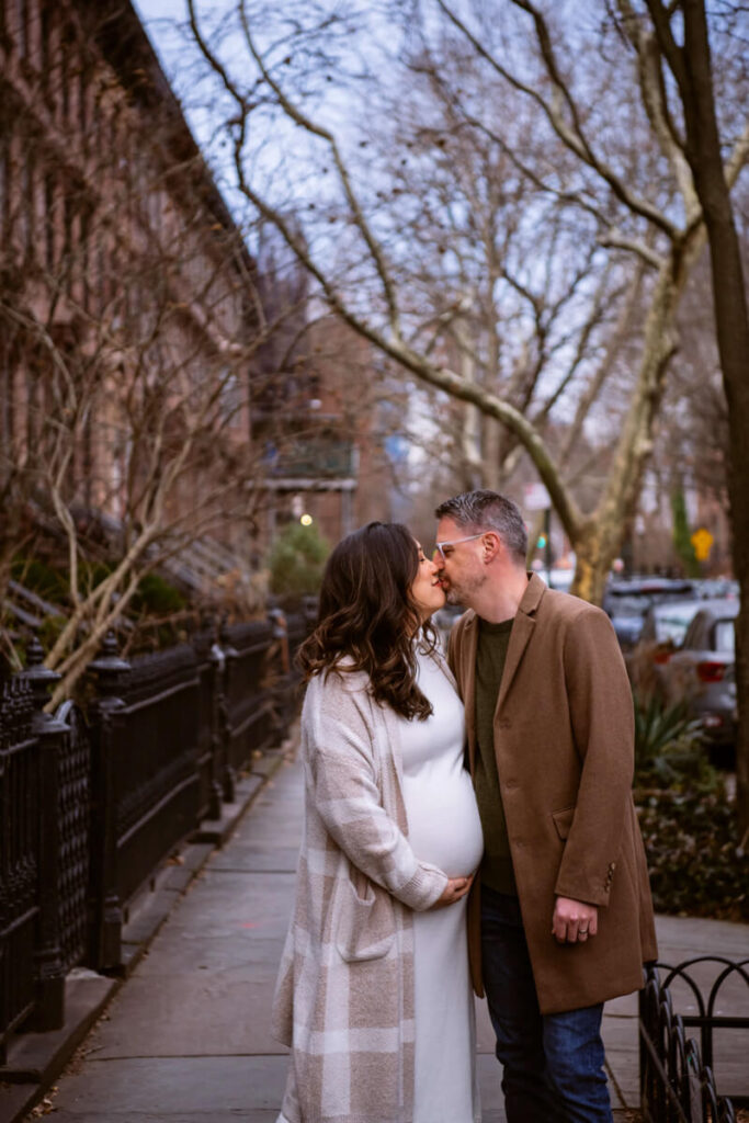 Husband and wife kiss on a Brooklyn sidewalk in the winter. She is holding her baby bump with one hand.

Brooklyn Maternity Portraits. Brooklyn Family Photography. NYC Maternity Photographer.