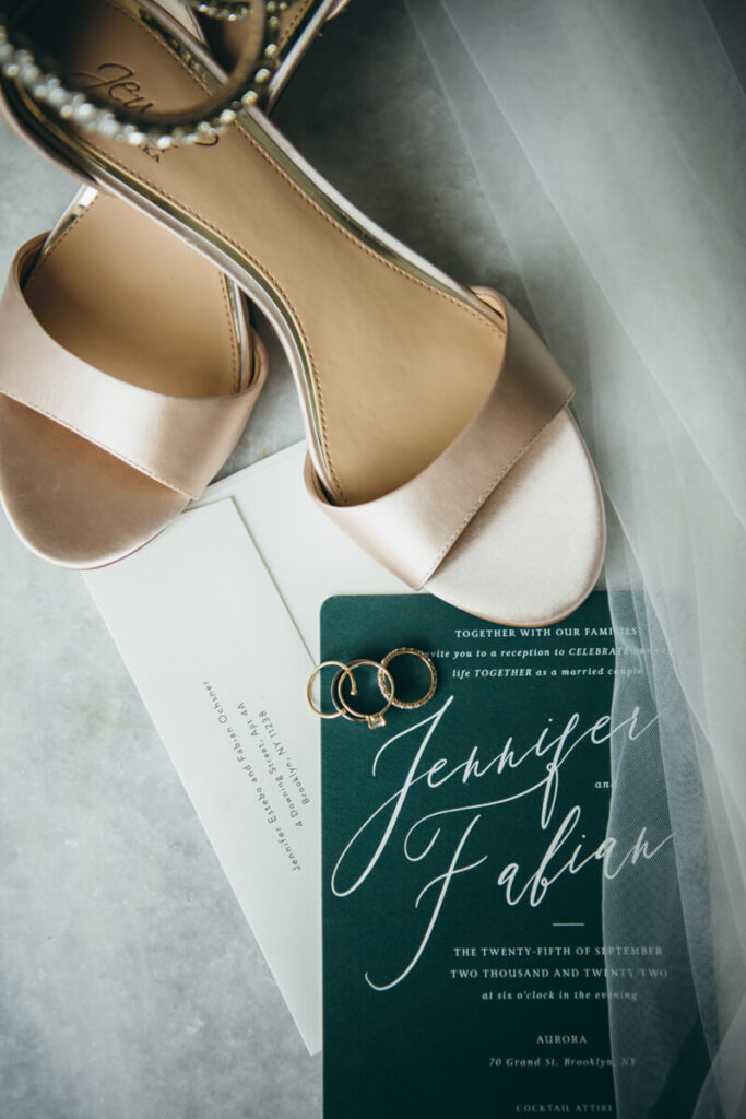 Close-up image of weddings rings and engagement ring with wedding invitations, veil, and the bride's heels.

NYC Wedding Portraits. Brooklyn Wedding Photographer. Luxury Local Wedding Photography.