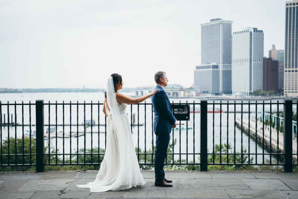 Groom stands on the Brooklyn Heights Promenade and the bride taps his shoulder from behind.

NYC Wedding Portraits. Brooklyn Wedding Photographer. Luxury Local Wedding Photography.