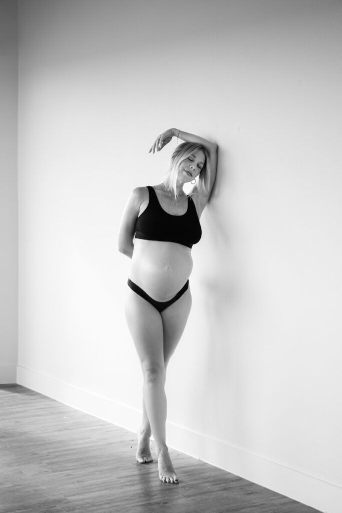 Pregnant woman stands next to a wall on her tiptoes with her hand reaching above her on the wall, wearing black underwear and black bra.

Austin Maternity Photography. Austin Maternity Photographer. Austin Maternity Portraits. 
