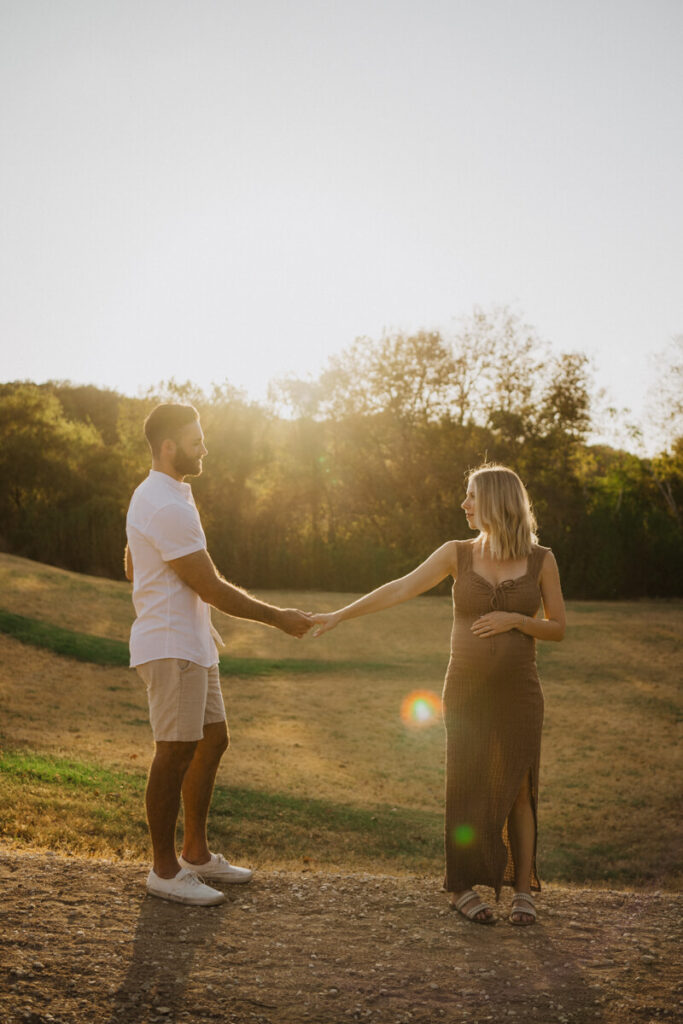 Husband and pregnant wife stand a few feet apart in a field, reach out to hold each other's hands. Maternity session photographed at Zilker Park in Austin.

Zilker Maternity Portraits. Austin Photography. Zilker Maternity Photographer.