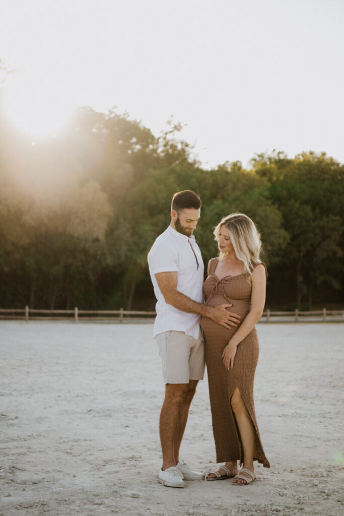 Husband and pregnant wife stand facing each other, husband has his hand on his wife's baby bump. Maternity session photographed at Zilker Park in Austin.

Zilker Maternity Portraits. Austin Photography. Zilker Maternity Photographer.