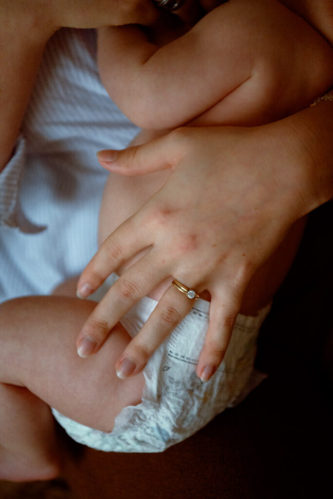 Close up of mother's hand holding her baby. Baby is wearing a diaper and mother is wearing a wedding ring.

Newborn Photography. Austin Newborn Photographer. Lifestyle Newborn Portraits. Austin Baby Portraits. Austin Famly Photography.