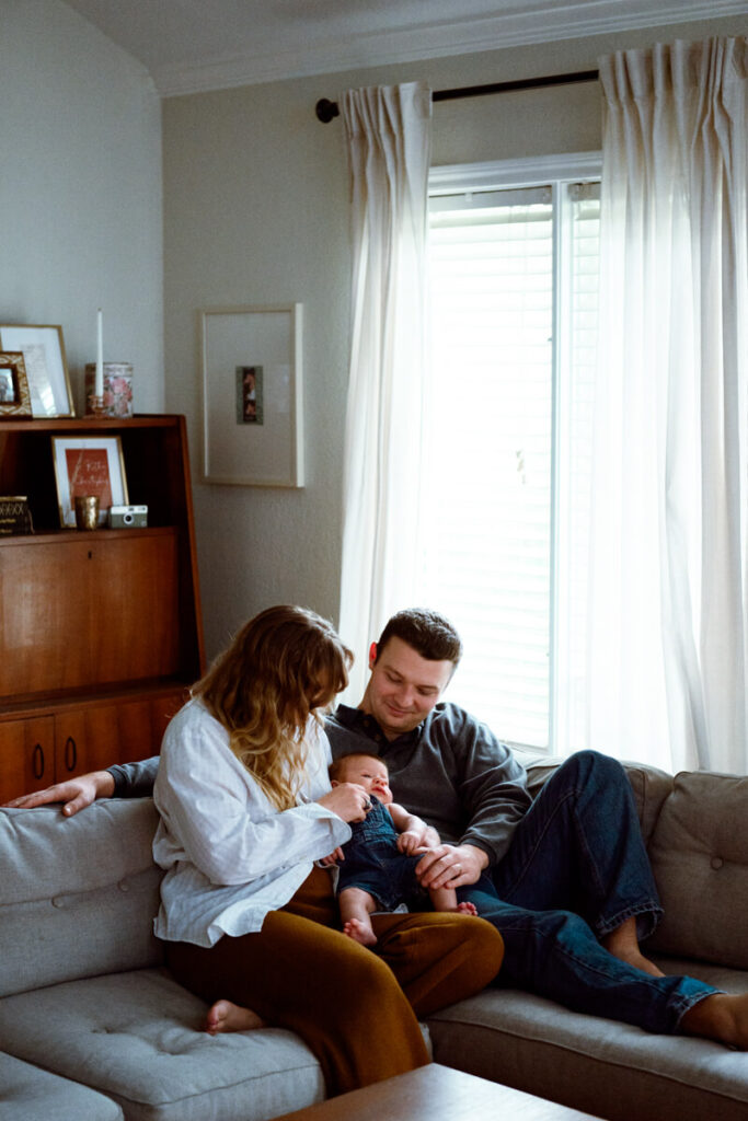 Mother, father, and their newborn baby all sit on a couch in their Austin, TX, home. Mother and father are looking lovingly down at their newborn baby.

Newborn Photography. Austin Newborn Photographer. Lifestyle Newborn Portraits. Austin Baby Portraits. Austin Famly Photography.