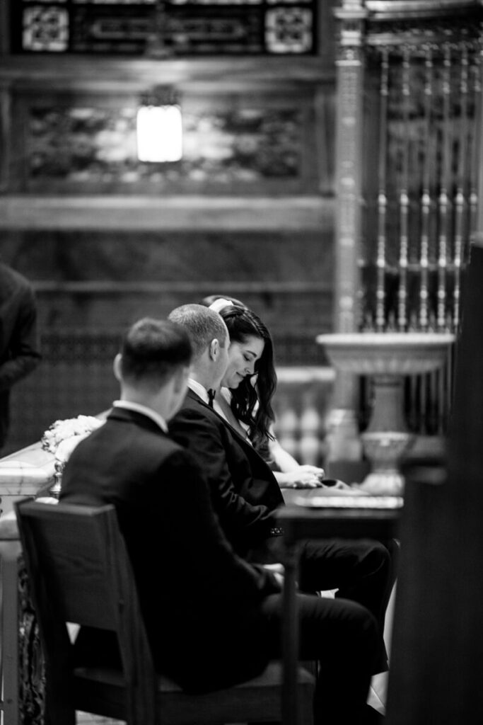 Bride is seated next to her groom and others. Se looks down, smiling. Black and white photograph.

Luxury NYC Wedding Photography. Manhattan Luxury Wedding Photographer. NYC Luxury Wedding. University Club Wedding Photographer.