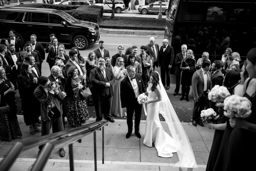 Bride and groom stand outside the Church of St. Ignatius Loyola with their wedding guests crowded around them with Park Avenue behind them. Black and white photograph.

Luxury NYC Wedding Photography. Manhattan Luxury Wedding Photographer. NYC Luxury Wedding. University Club Wedding Photographer.