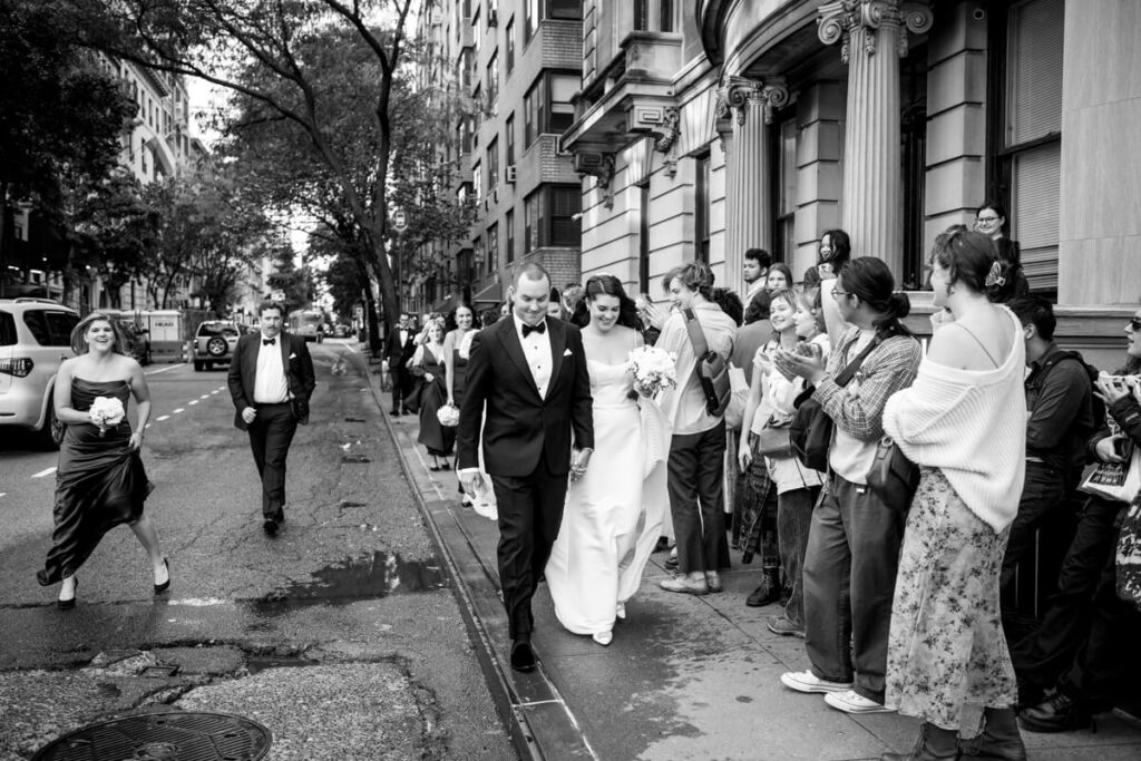 Bride and groom are holding hands, walking down the streets of NYC, while onlookers clap and smile as they pass. Black and white photograph.

Luxury NYC Wedding Photography. Manhattan Luxury Wedding Photographer. NYC Luxury Wedding. University Club Wedding Photographer.