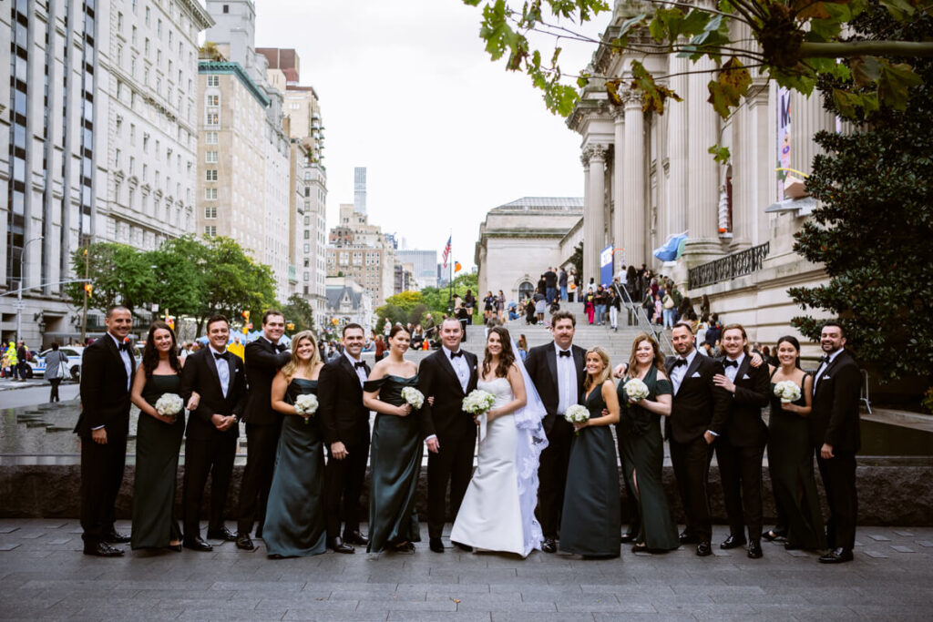 Bride, groom, and their entire bridal party lined up and smiling at the camera. The Metropolitan Museum of Art is in the background.

Luxury NYC Wedding Photography. Manhattan Luxury Wedding Photographer. NYC Luxury Wedding. University Club Wedding Photographer. 5th Avenue Bridal Party Portraits.