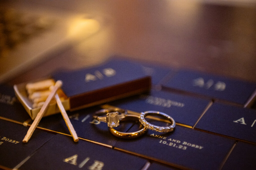 Close up photograph of the wedding rings alongside boxes of matches with "Anne and Bobby 10.21.23" printed on them.

Luxury NYC Wedding Photography. Manhattan Luxury Wedding Photographer. NYC Luxury Wedding. University Club Wedding Photographer.