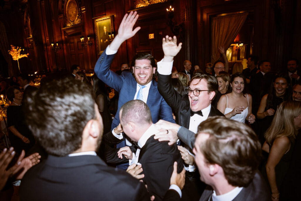 Wedding guests are jumping and dancing surrounding the groom on the dance floor in the University Club in Manhattan.

Luxury NYC Wedding Photography. Manhattan Luxury Wedding Photographer. NYC Luxury Wedding. University Club Wedding Photographer.