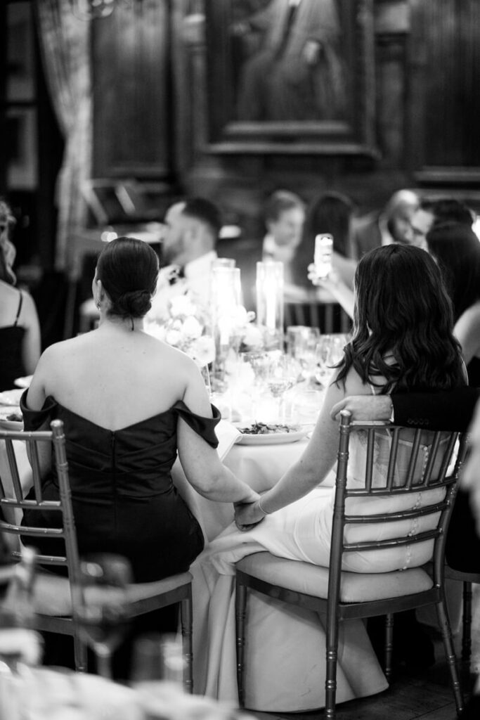 Bride and one of her bridesmaids are sitting in chairs next to each other. Photographed from behind, they are holding hands. Black and white photograph.

Luxury NYC Wedding Photography. Manhattan Luxury Wedding Photographer. NYC Luxury Wedding. University Club Wedding Photographer.