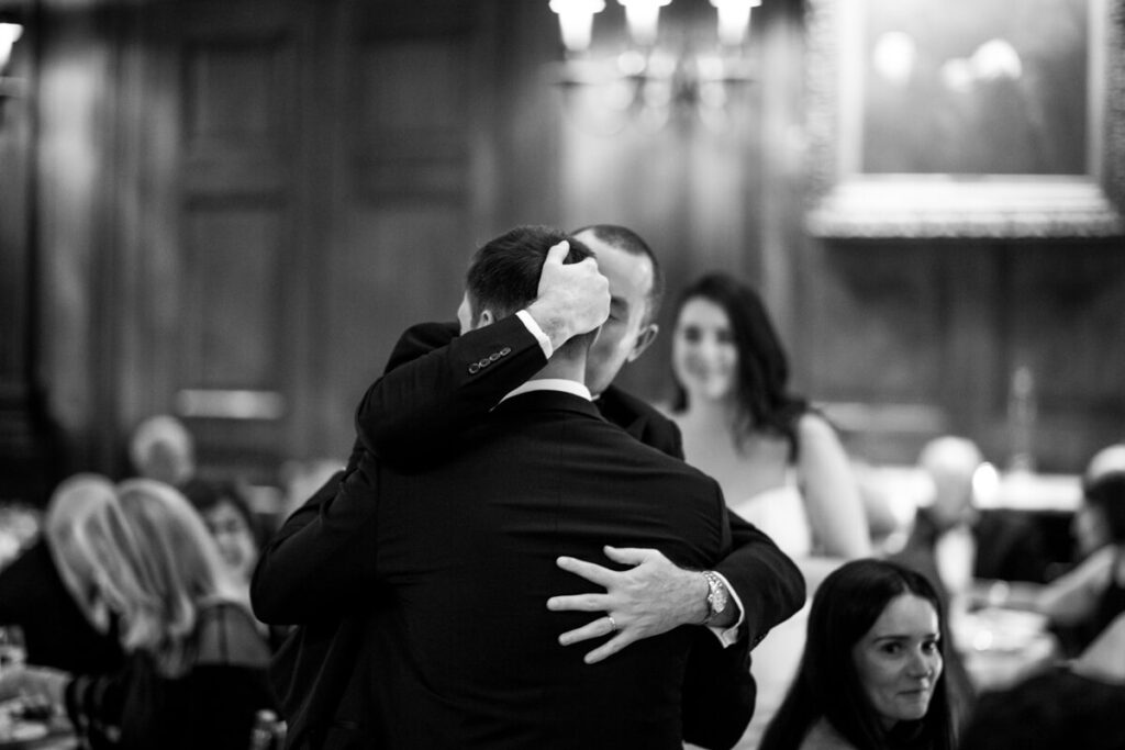 Groom kisses his best man on the cheek and wraps his arms around him. Bride looks on from the background. Black and white photograph.

Luxury NYC Wedding Photography. Manhattan Luxury Wedding Photographer. NYC Luxury Wedding. University Club Wedding Photographer.