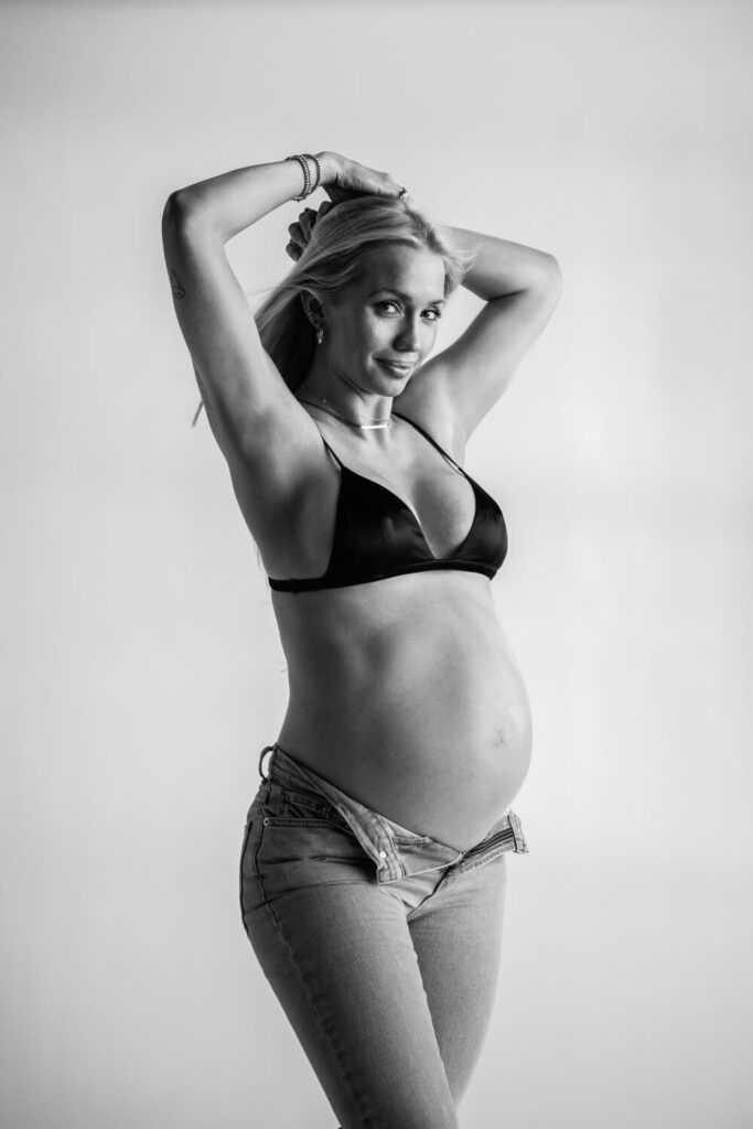 pregnant woman with Calvin Kleins inspired jeans black and white maternity photo smiling towards camera photographed by Austin maternity photographer Kat Harris 