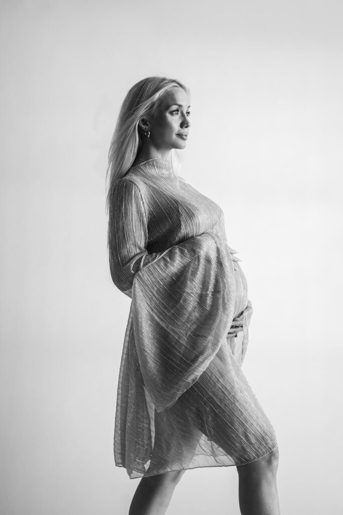 iconic black and white maternity photo with pregnant woman in flowy dress with white paper background photographed by Austin maternity photographer Kat Harris