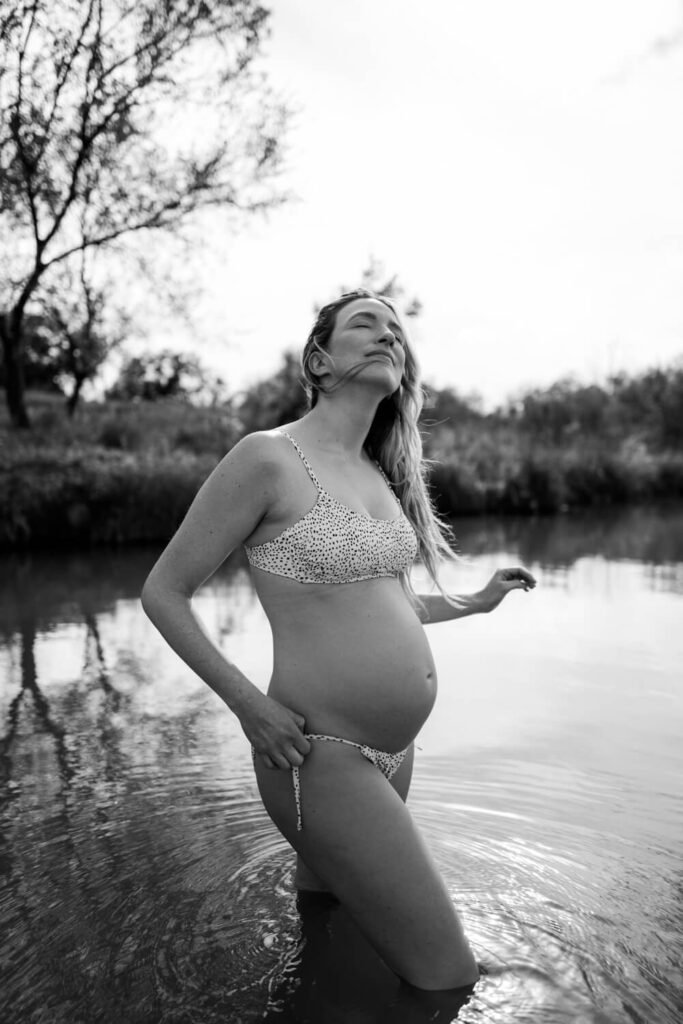 Timeless black and white portraits of a pregnant lady in town lake with the wind blowing her hair over her face photographed by Austin water maternity photographer Kat Harris.