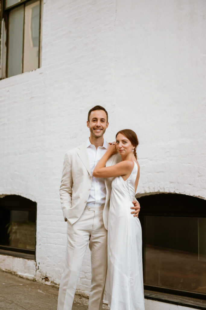 Classic portrait of couple embracing in front of a white brick wall during an engagement photo shoot in Williamsburg Brooklyn 