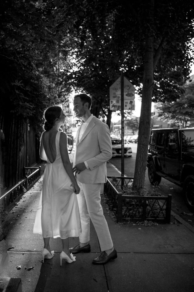 Classic black and white portraits of backlit couple pausing to talk with each other in between moments of their engagement photos on their way to Domino Park in Brooklyn.