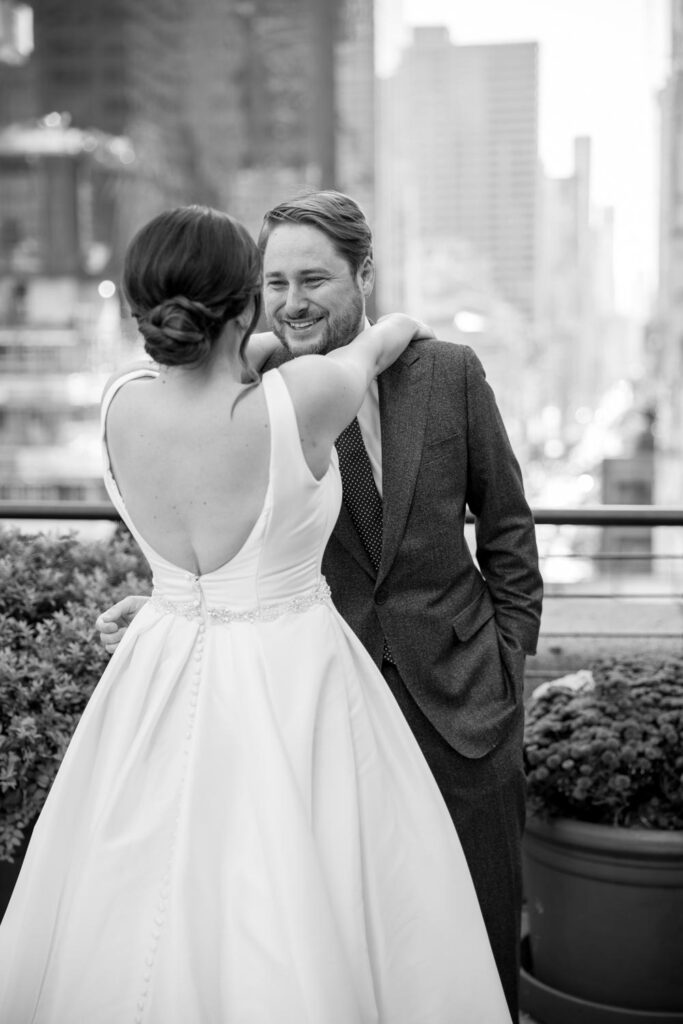 Groom seeing his bride for the first time and beaming as he sees her Pronovias gown at their rooftop terrace first look at the University Club photographed by New York City wedding photographer Kat Harris.