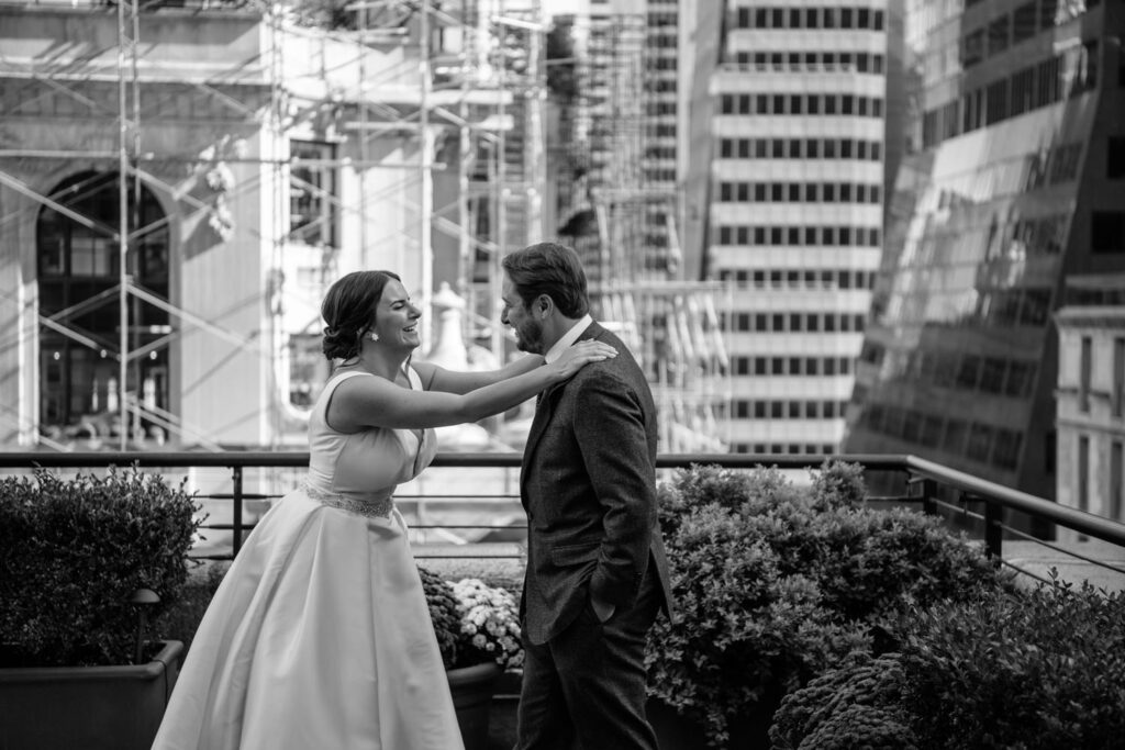 Bride and groom laughing as they share an intimate moment at their first look on the rooftop terrace of New York City's University Club photographed by New York City wedding photographer Kat Harris.