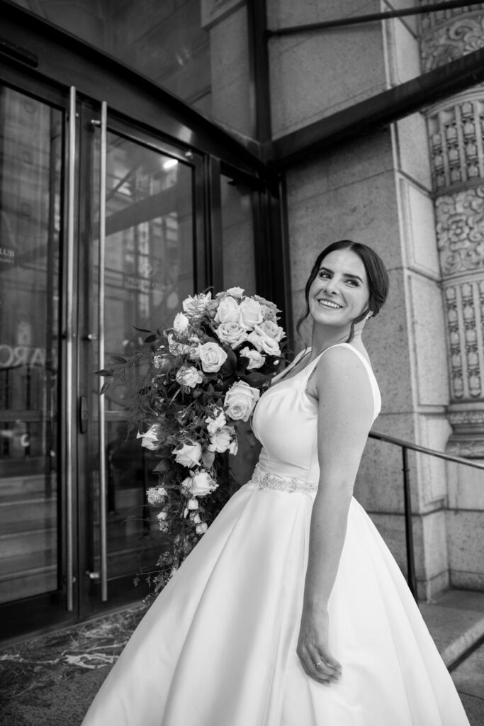 editorial bridal portraits of bride in Pronovias gown holding her bridal bouquet on the steps of New York City's University Club photographed by New York City wedding photographer Kat Harris.