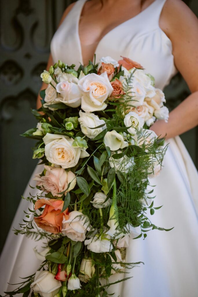 close up detail photo of the bridal bouquet full of pink, cream, and peach rose flowers and greenery photographed by New York City wedding photographer Kat Harris.