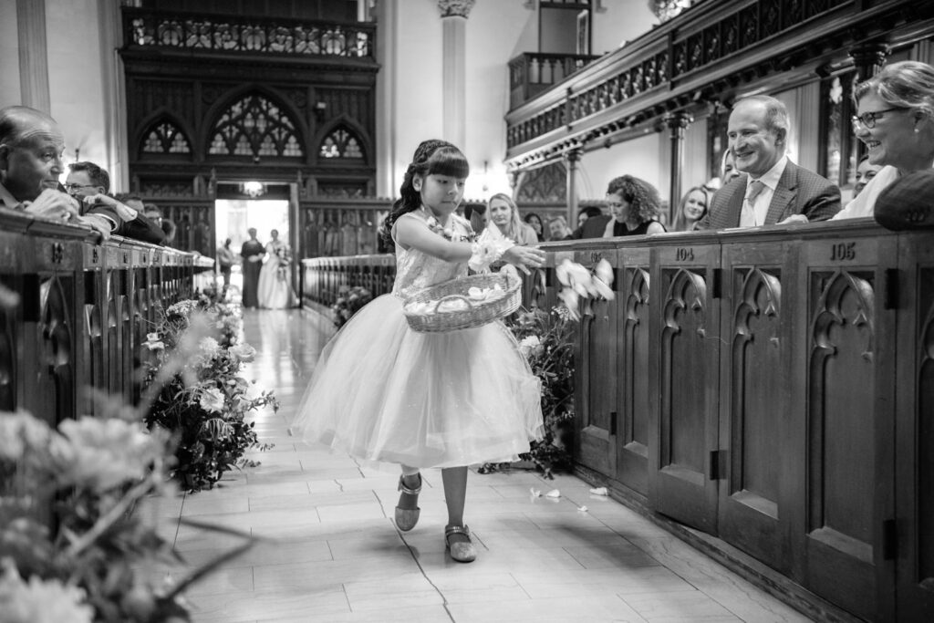 flower girl walking down the aisle throwing rose petals in preparation for the bride at the wedding ceremony at The First Presbyterian Church on 12th street and 5th ave photographed by New York City wedding photographer Kat Harris.