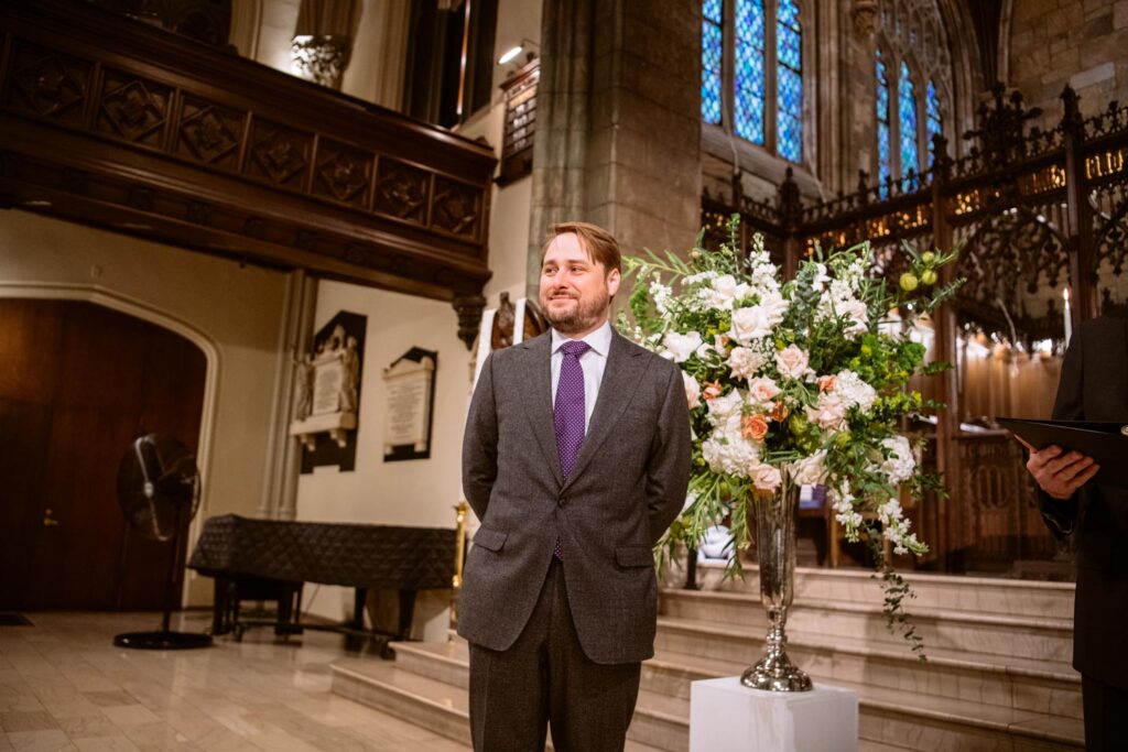 Groom standing at the front of the church awaiting his bride as she walks up the aisle at The First Presbyterian Church on 12th street and 5th ave photographed by New York City wedding photographer Kat Harris.