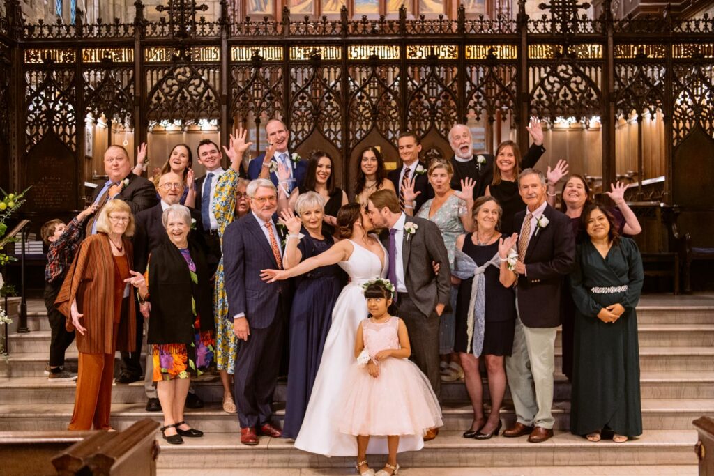 Large family photo on the steps of the church after the wedding ceremony with everyone smiling and laughing and cheering on the happy couple at The First Presbyterian Church on 12th street and 5th ave photographed by New York City wedding photographer Kat Harris.