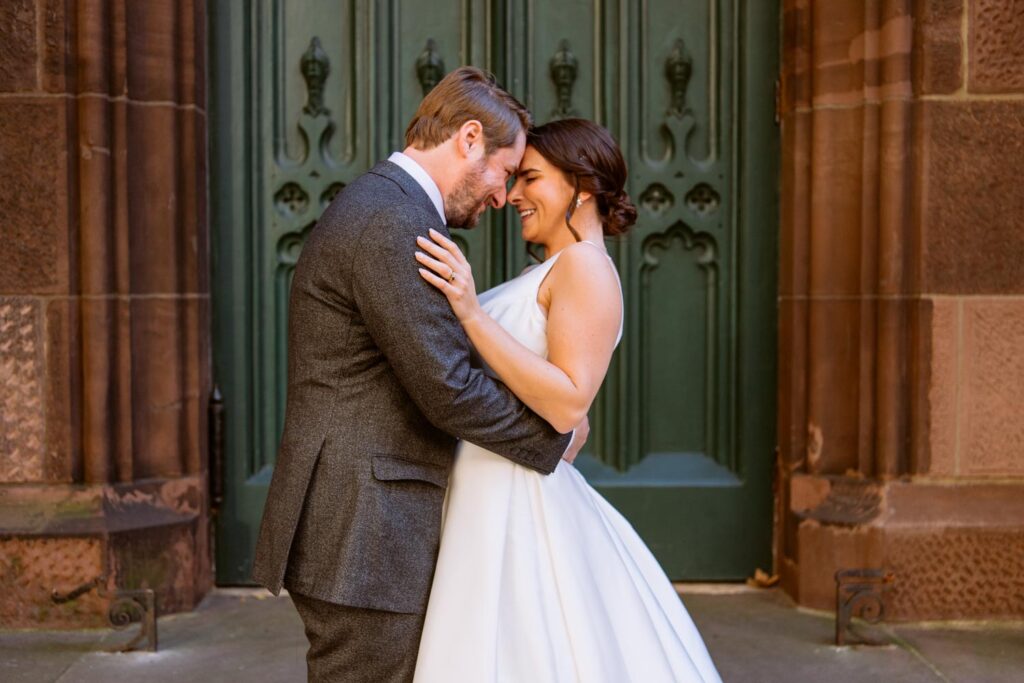 bride and groom hug forehead to forehead outside of the church before heading to their wedding reception at New York's University Club photographed by New York City wedding photographer Kat Harris.