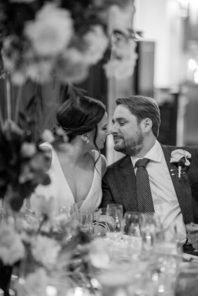 bride and groom share a brief kiss during the wedding reception as toasts begin photographed by New York City wedding photographer Kat Harris.