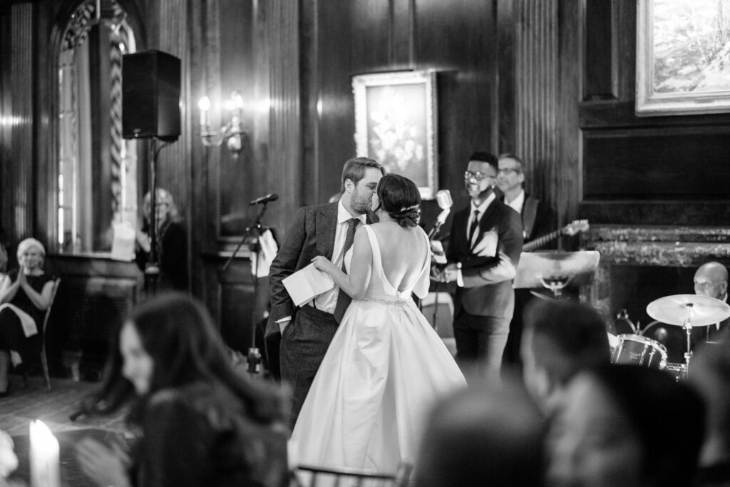 Bride and Groom share a kiss during speeches at their University Club wedding reception photographed by New York City wedding photographer Kat Harris.