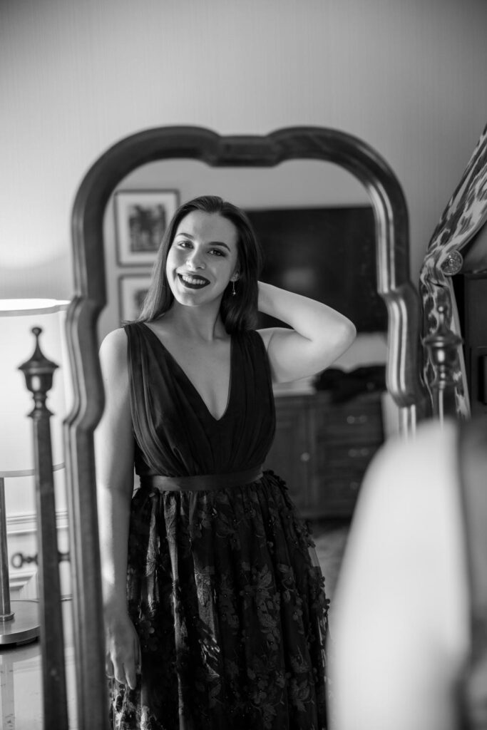 Maid of Honor looking in the mirror fixing her hair and smiling as she gets ready for the wedding day in the University Club of New York Bridal Suite photographed by New York City wedding photographer Kat Harris.